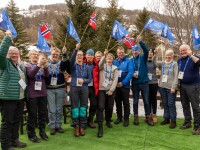 A group of people standing in a row waving flags. 