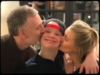 Mother and father kissing their son on the cheeks. 