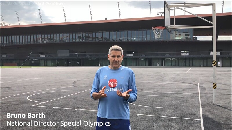 Bruno Barth on the basketball court with a Play Unified long sleep blue shirt on talking to the camera.