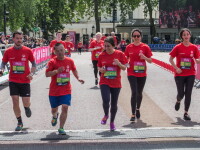 Runners in red t-shirts running towards the camera across a finish line. 