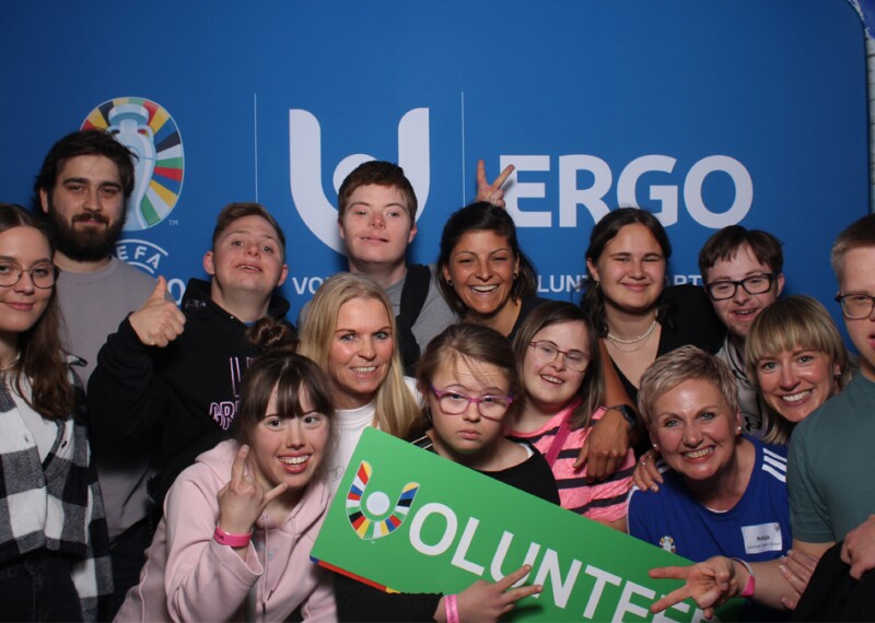 Group photo with people in the front holding a "volunteer" sign. 