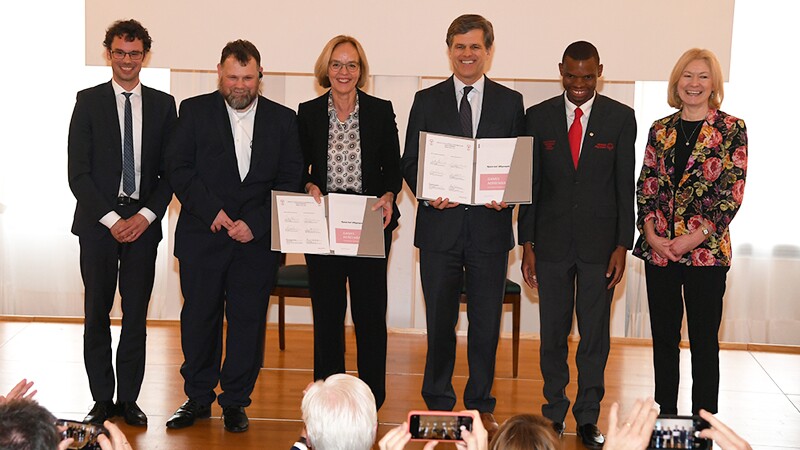 Six Special Olympics representatives standing on stage holding the Berlin signing and posing for group photos.