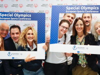 Attendants to the SOEE Sports Conference smiling at the camera while holding branded signs
