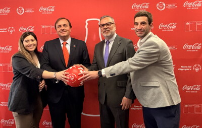Four people posing for a photo while holding a Special Olympics-branded football.
