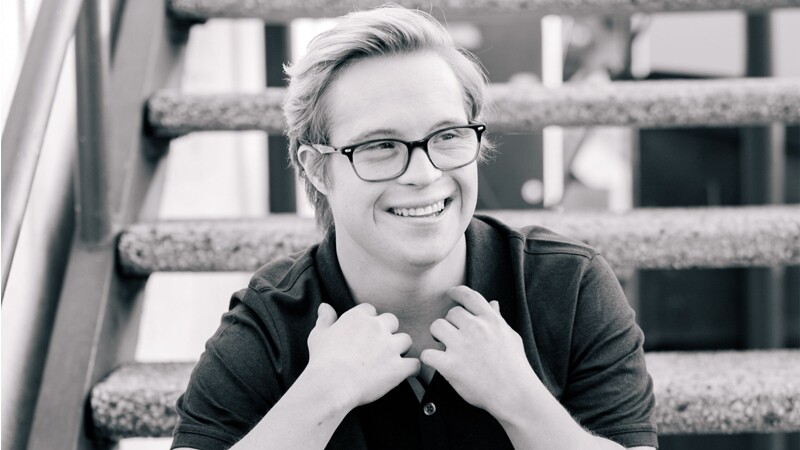Cole sitting on a set of stairs looking into the distance and smiling.