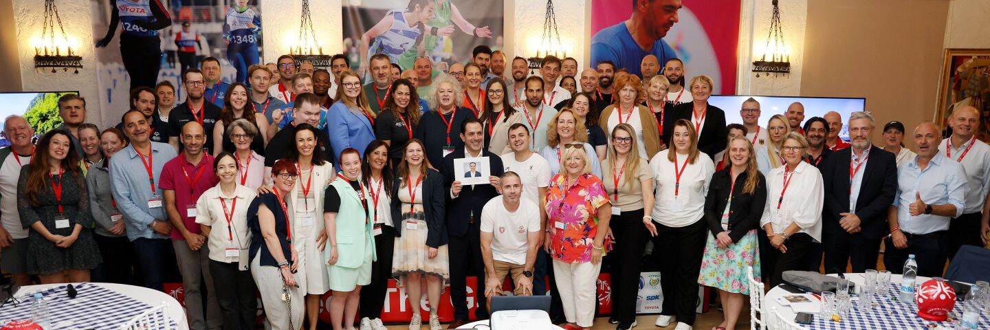 A large group of people stand together smiling and facing the camera.