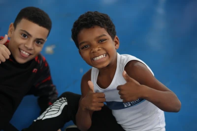 Dos niños sonriendo en una cancha deportiva durante una actividad inclusiva de Olimpiadas Especiales.