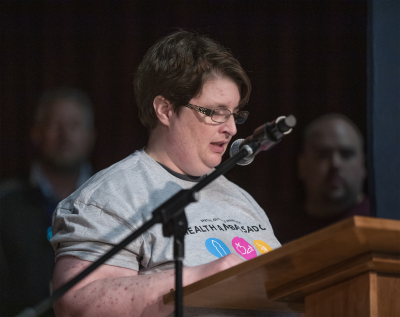 Woman standing at a podium speaking. 