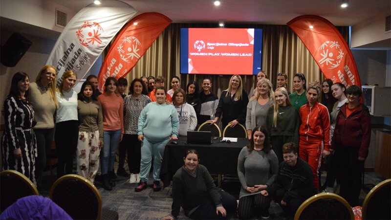 Mujeres jóvenes en el interior, paradas en dos filas para una foto de grupo. 