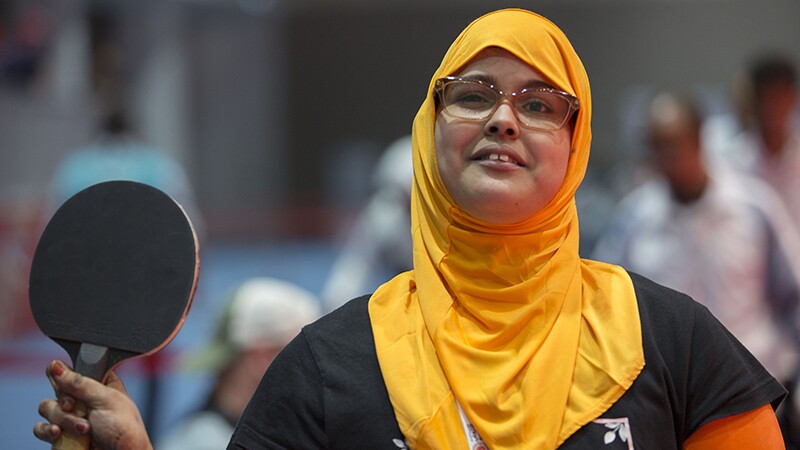 Khadija standing with her paddle in had ready to play.