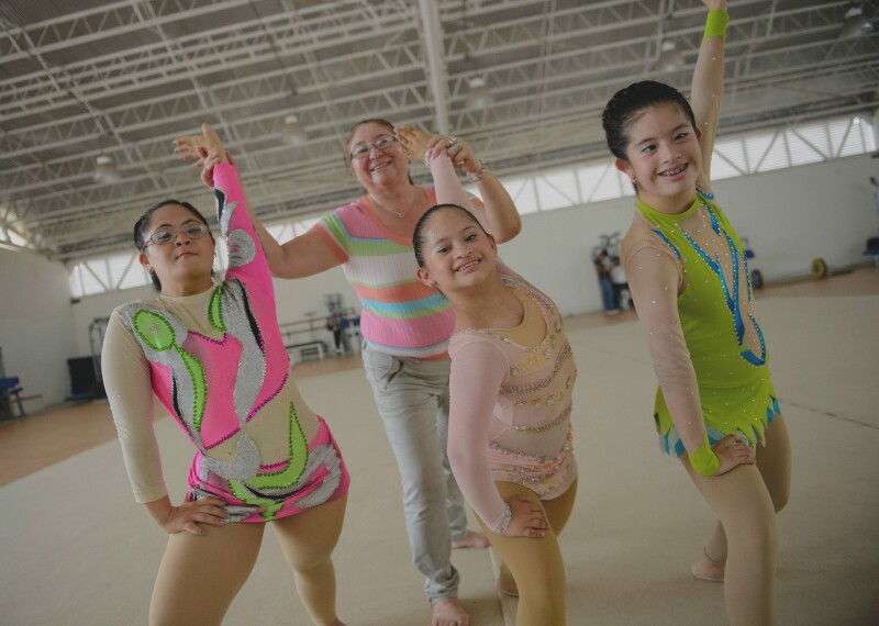 Three athletes pose while a coach assists with hand techniques.