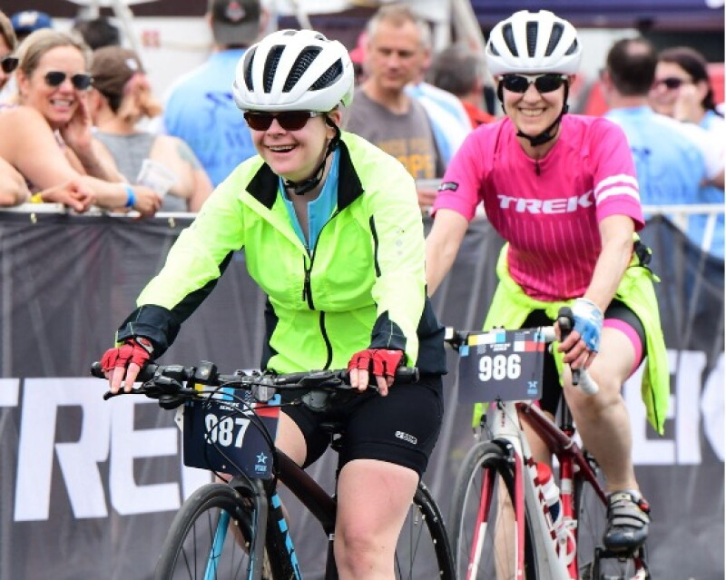 Two women ride bicycles in a road race.