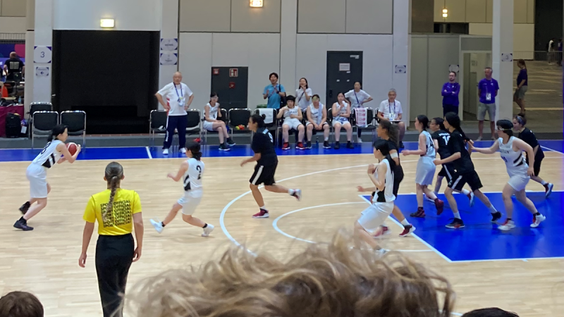 Women's teams playing basketball on a court. 