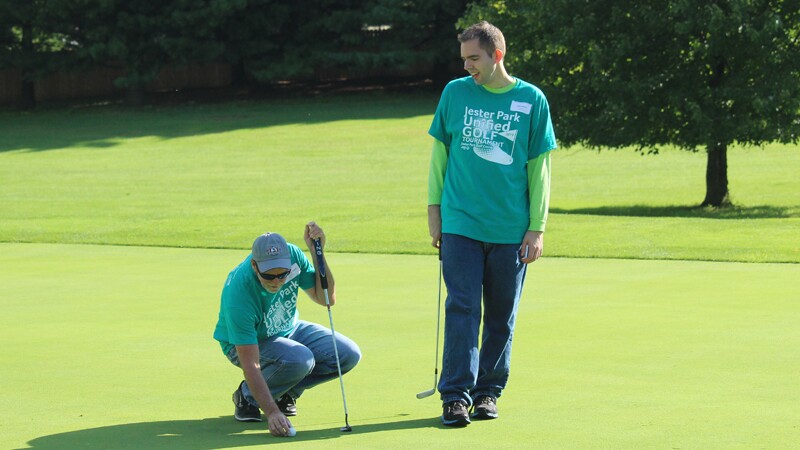 Tyler Leech on the green playing golf with another player.