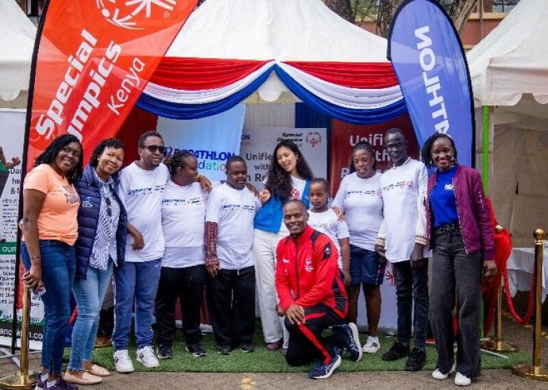 A group of people stand together smiling with Special Olympics Kenya and Decathlon branding in the background.