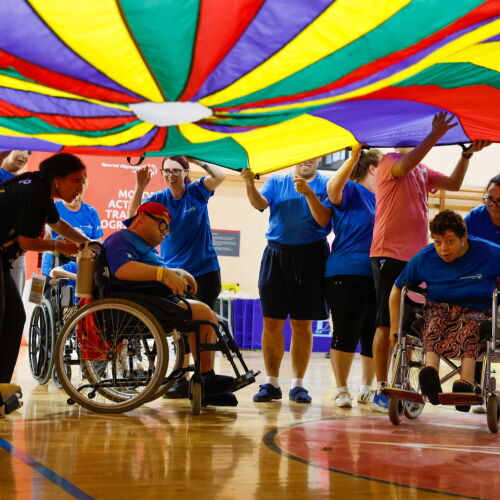 A group of athletes waving a huge, colourful cloth over their heads
