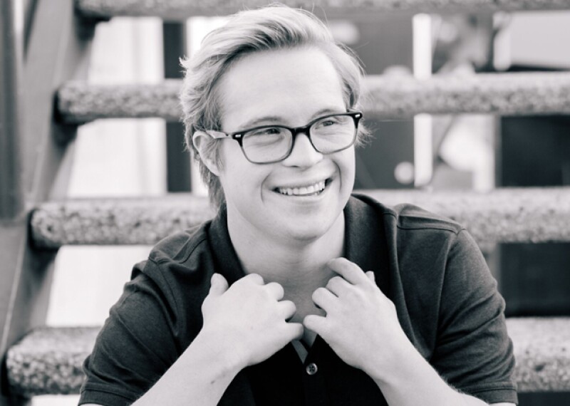 Cole sitting on a set of stairs looking into the distance and smiling. 