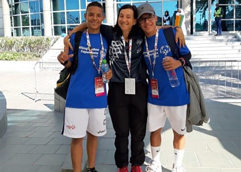 Coach Maria at World Games Abu Dhabi 2019 standing with two athletes on either side of her in front of the pavilion.