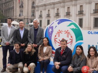 A group of 10 people in two rows in front of Santiago 2027 branded signage. 