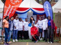 A group of people stand together smiling with Special Olympics Kenya and Decathlon branding in the background.