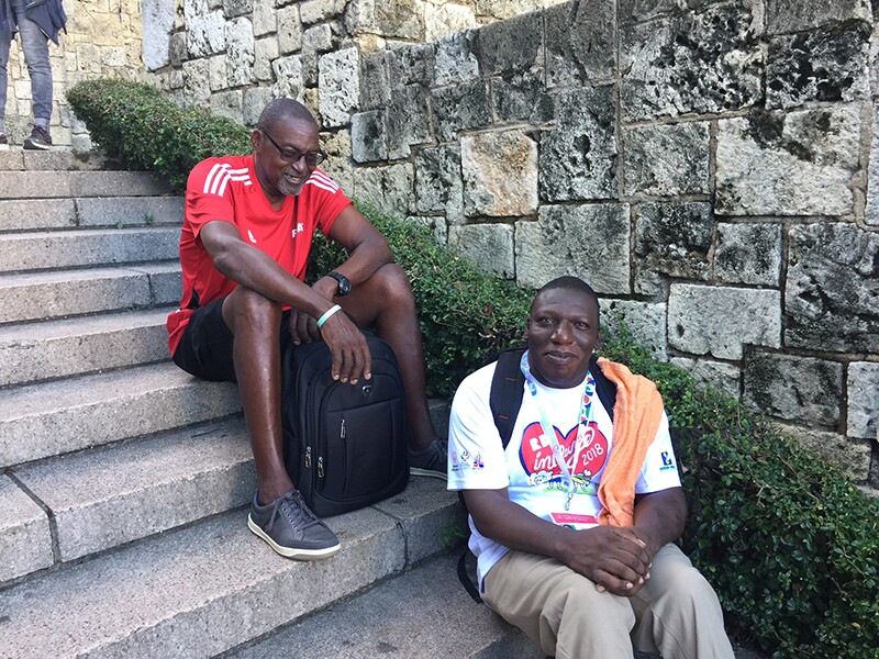 Athlete, Terrence Davis, and another person sitting on concrete steps next to a brick wall.