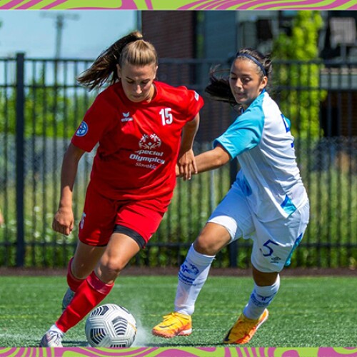 Two girls on the pitch playing football. 