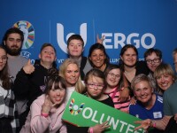 Group photo with people in the front holding a "volunteer" sign. 