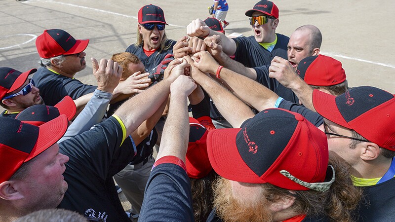 Group of sorts persons putting their hands together in a circular huddle.