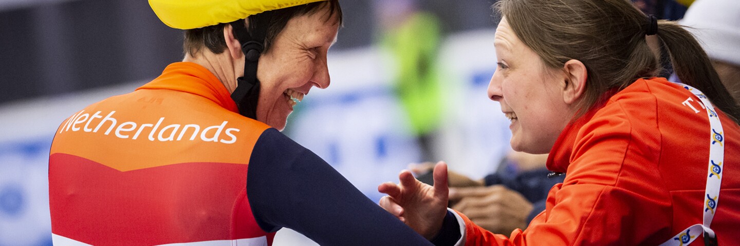 Coach and athlete interacting and smiling with one another.