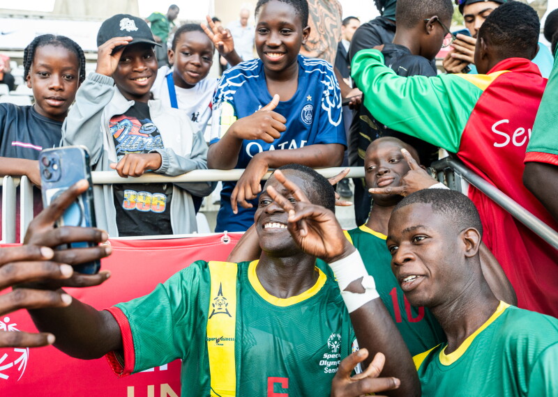 Two Special Olympics Senegal players posing with fans in the Stands