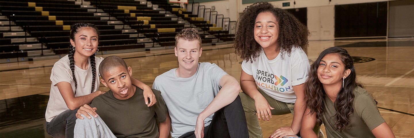 Five young adults in gymnasium together in a group. 