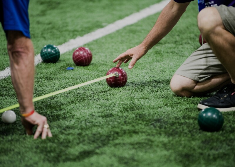 Official on the field measure the distance between two balls as a player observes.