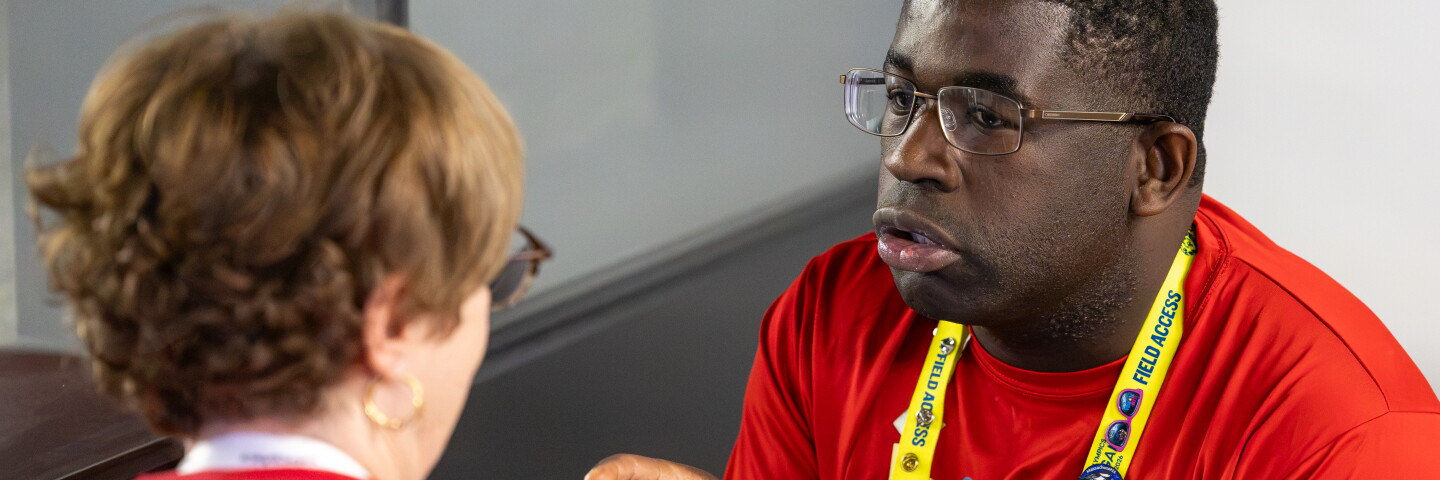 Man speaking and gesturing while a woman listens. 