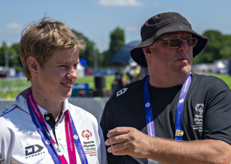 Young man and older man with awards around their necks. 