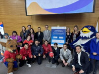 People both kneeling and smiling in a group posing for a photo alongside two mascots (bird and bull)