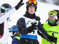 One Skier listening to another skier as a volunteer looks on. 