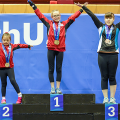 Three girls standing on a podium over their ranking. 