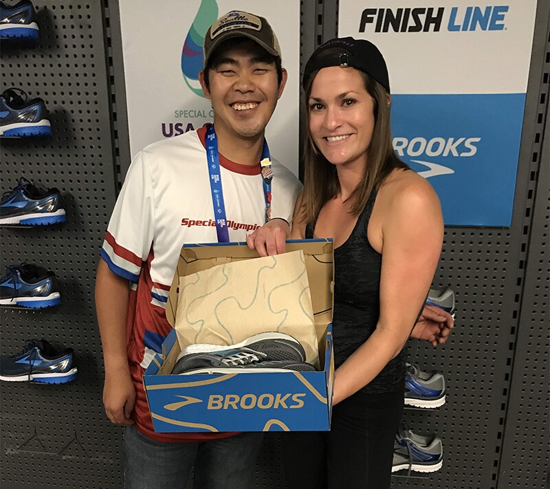 Finish Line Youth Foundation employee presents a Special Olympics athlete with a new pair of shoes