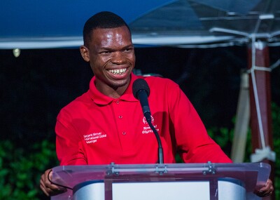 Nyasha standing behind a podium and smiling at the crowd. 