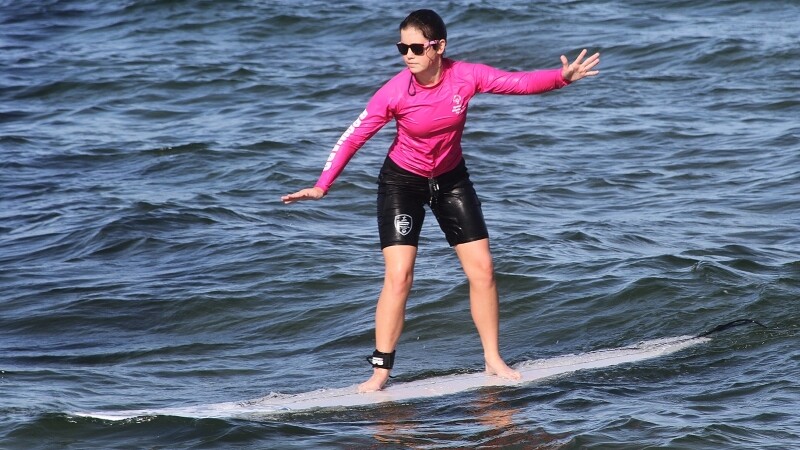 Special Olympics athlete surfs in the ocean. 
