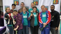 Special Olympics employees and friends (a group of 9) in front of a Best Buddies back drop.