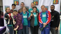 Special Olympics employees and friends (a group of 9) in front of a Best Buddies back drop. 