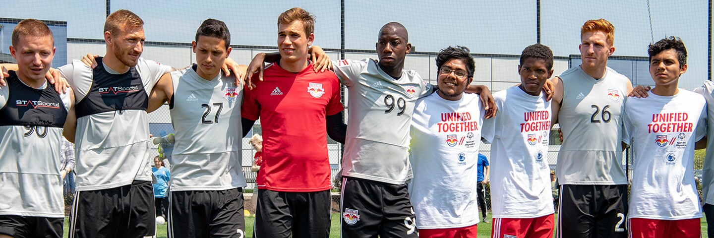 Group of footballers with their arms around one another's shoulders standing in a group.