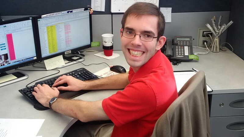 Tyler Leech sitting at his desk, turning around and smiling for a photo.