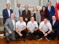 Eight people dressed in formal attire and three others wearing Special Olympics Gibraltar uniforms are standing together, posing for a group photo.
