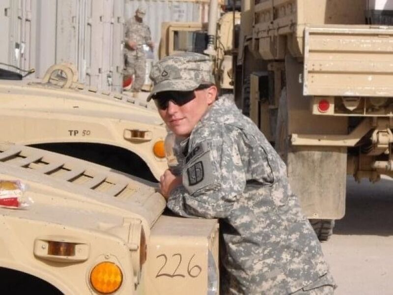 Monica Klock leans on a military vehicle while in Iraq.
