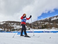 Female cross-country skier in action on the snow with mountains in the background