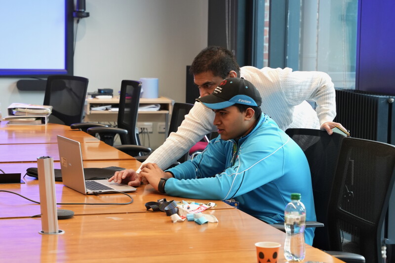 Two people at a table working on a computer. 