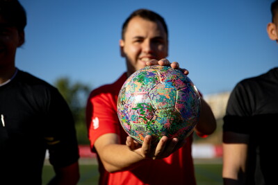 Un joven atleta sostiene y exhibe un balón de fútbol americano.
