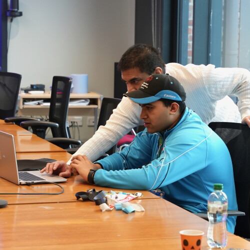 Two people at a table working on a computer. 